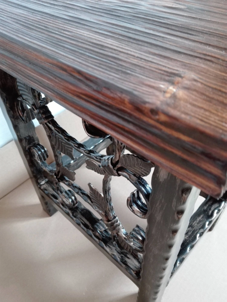Detail hrany sedáku z masivního smrku o tloušťce 4 cm nad kovanými ornamenty