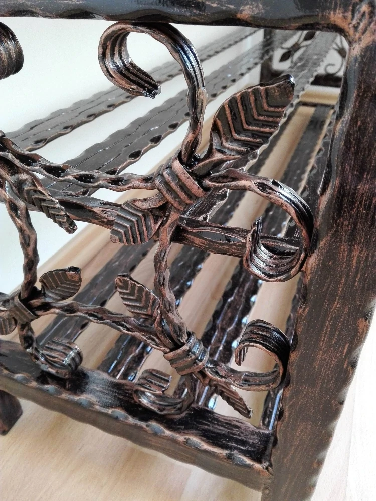 Detail zdobených ocelových tyčí a spirál na boku botníku