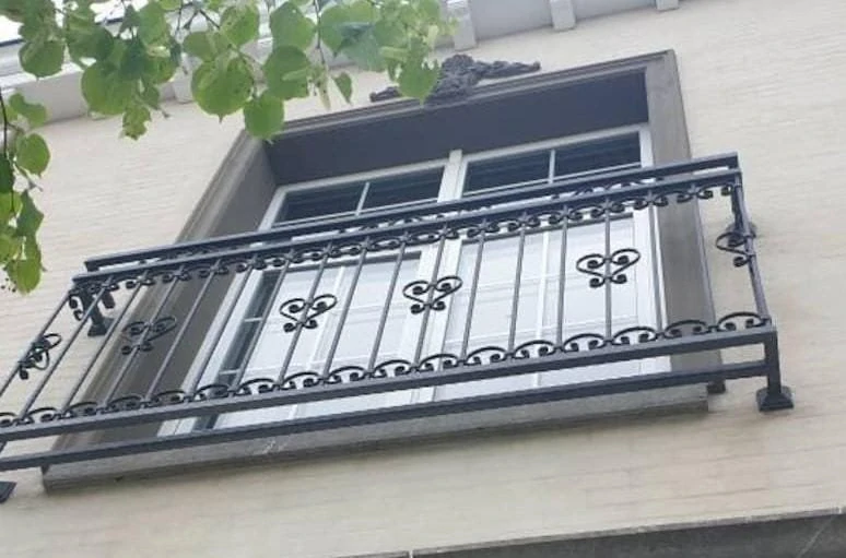 Kované zábradlí na okno se srdíčky, pohled zdola na světlé fasádě