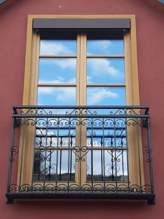 Francouzský balkon na míru – černé kované zábradlí na francouzské okno se srdíčky na červené fasádě